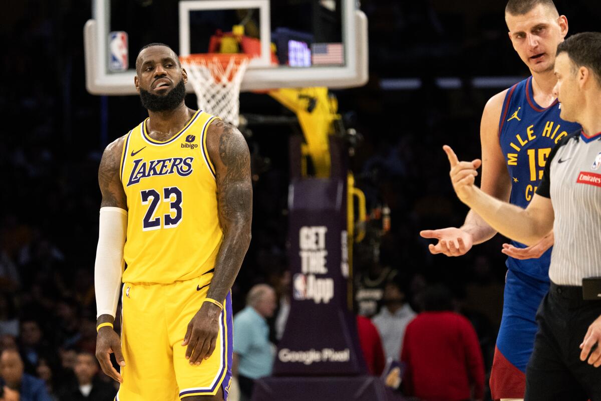 La estrella de los Lakers, LeBron James, mira al centro de los Denver Nuggets, Nikola Jokic, y a un árbitro.