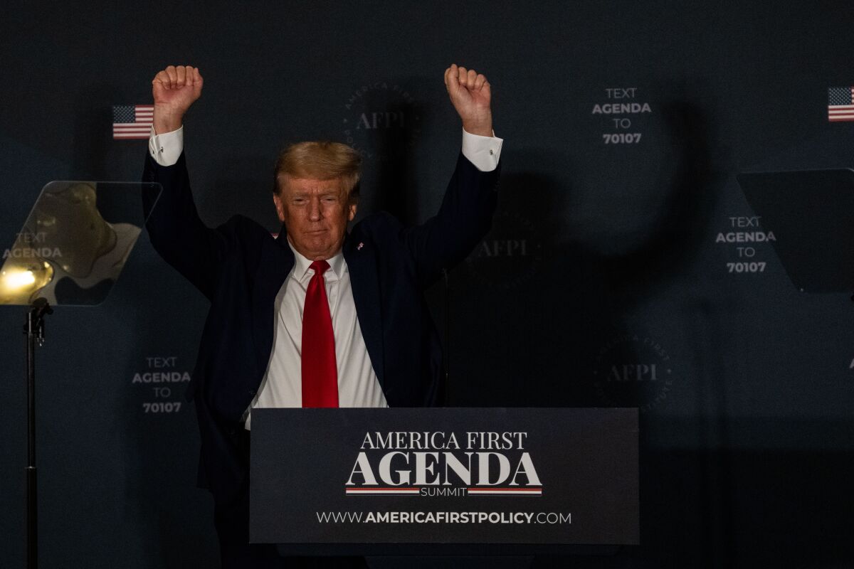 Former President Trump raises his arms.