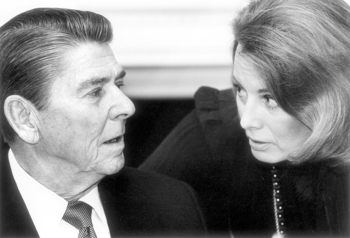 President Ronald Reagan talks with Deputy Press Secretary Karna Small-Bodman in the State Dining room at a luncheon for editors in 1983.