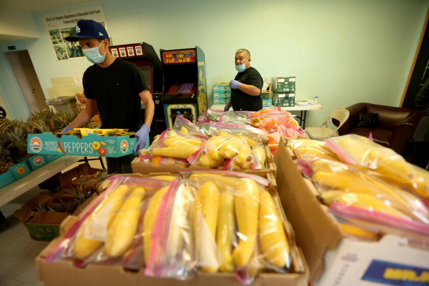 Jesus Saquic and Ramiro Quezada prepare bags of canned foods, vegetables and rice at the weekly food giveaway.