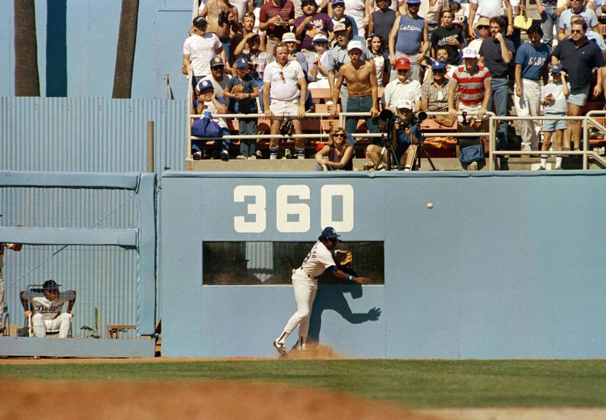 Dodgers left fielder Pedro Guerrero runs into the wall trying to catch a double.