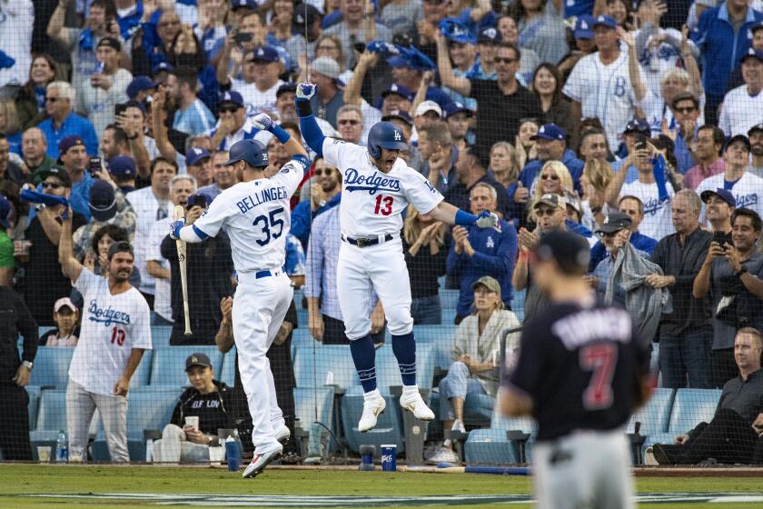 LOS ANGELES, CA - OCTOBER 9, 2019: Los Angeles Dodgers first baseman Max Muncy (13) celebrates with on-deck batter Los Angeles Dodgers Cody Bellinger (35)after Muncy hit a 2- run homer off Washington Nationals starting pitcher Stephen Strasburg (37) to give the Dodgers a 2-0 lead in the 1st inning of Game 5 of the NLDS at Dodger Stadium on October 9, 2019 in Los Angeles, California. (Gina Ferazzi/Los AngelesTimes)