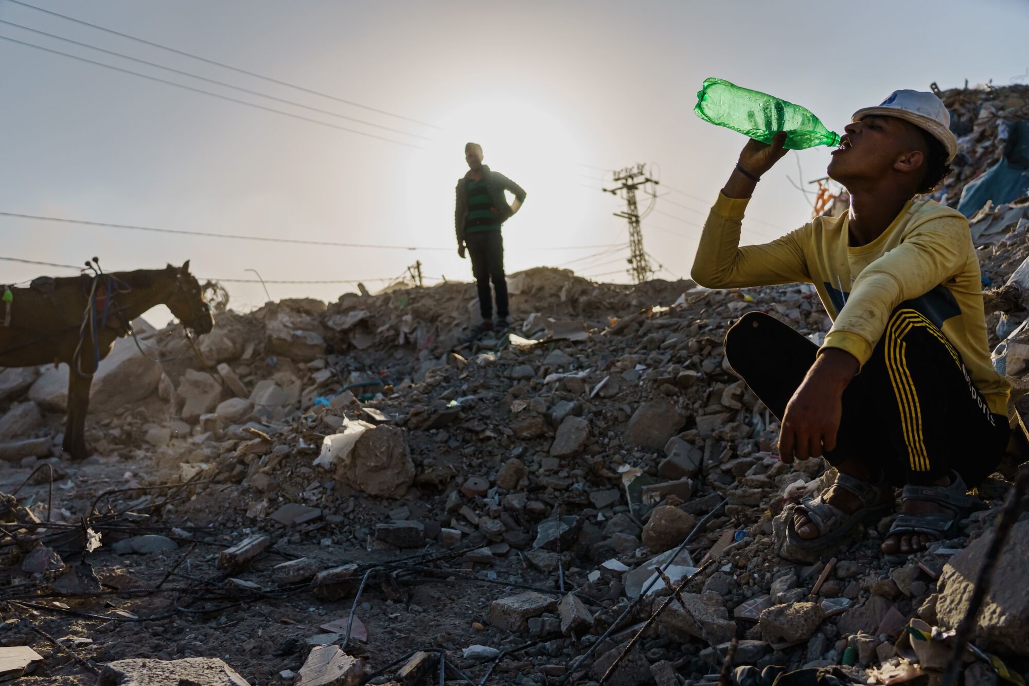  A worker drinks from a bottle during a break on a rubble pile 