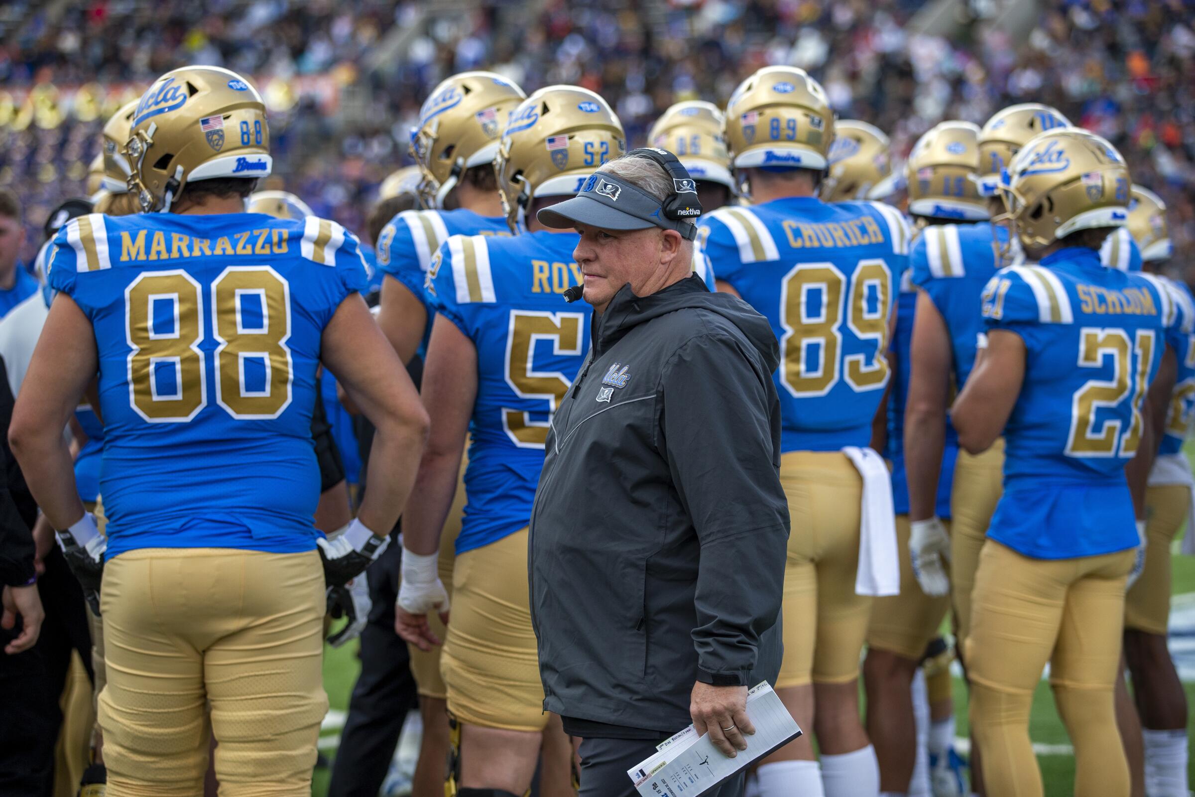 UCLA coach Chip Kelly walks back to the sideline during a time out in front of a group of Bruins players.