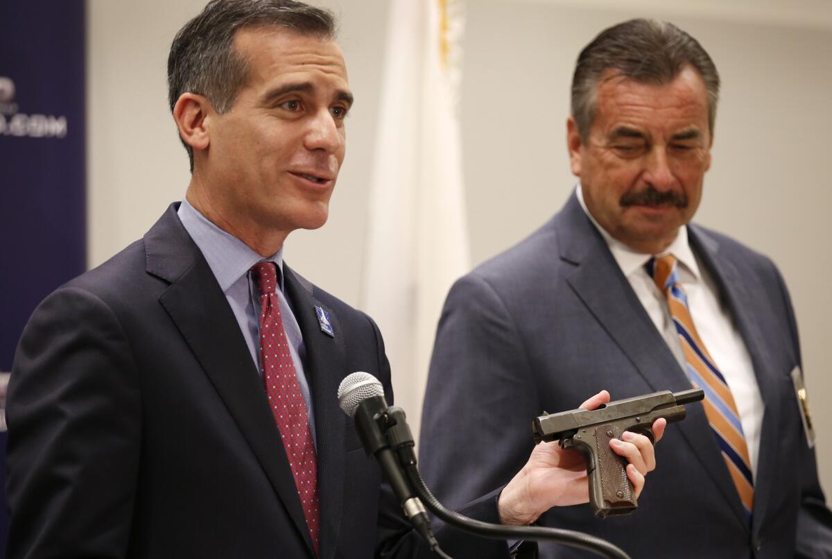 Los Angeles Mayor Eric Garcetti holds a vintage pistol that was registered to Sammy Davis Jr., as he and L.A. Police Chief Charlie Beck discuss results from a gun buyback event this last weekend.