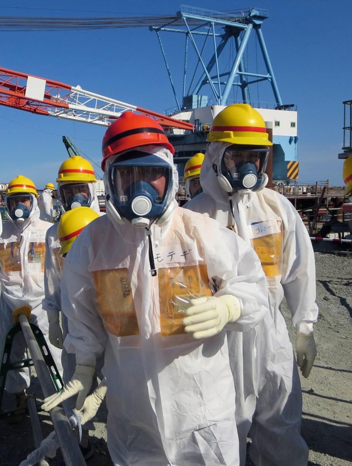 Toshimitsu Motegi, in orange helmet, Japan's minister of economy, trade and industry, visits the crippled Fukushima Daiichi Nuclear Power Station in August.