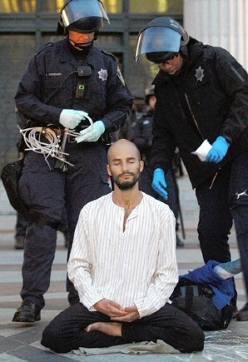 A protester meditates as police move in to arrest him at Occupy Oakland on Monday.