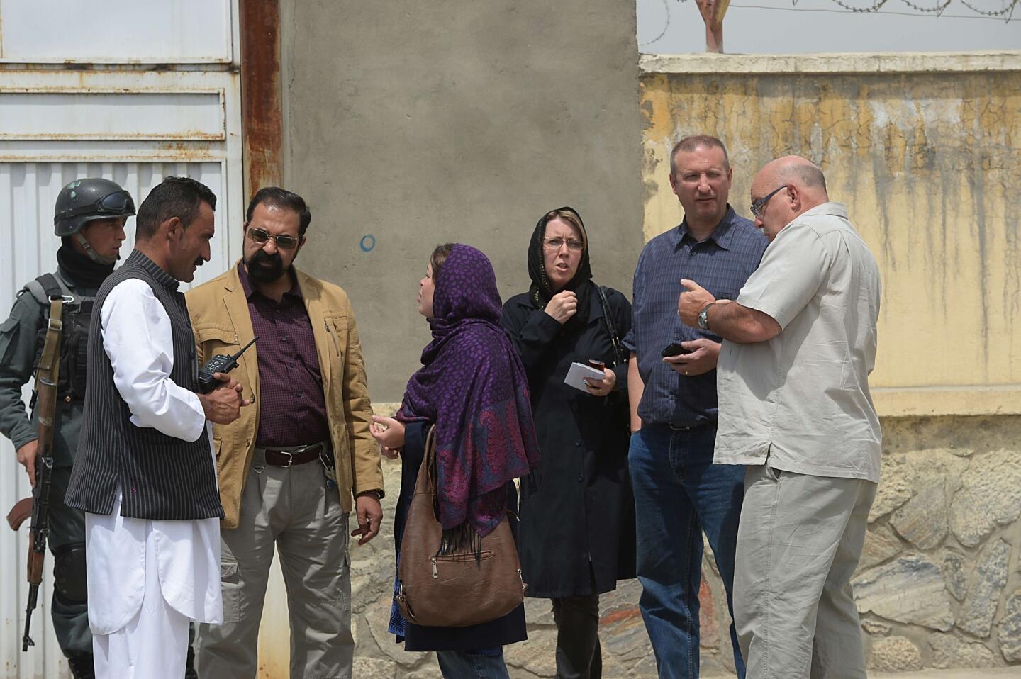 Foreign nationals talk with Afghan security personnel at the gate of the Cure hospital in Kabul.
