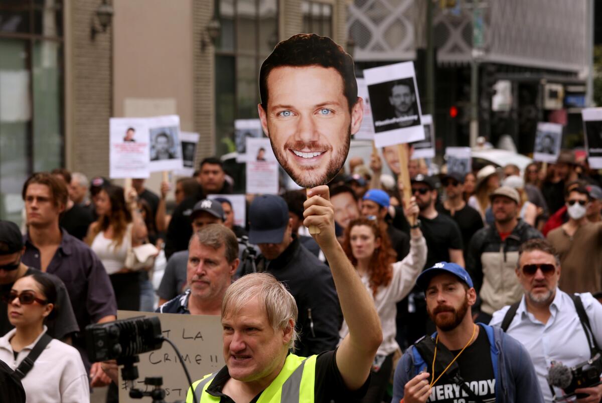 People carry pictures of actor Johnny Wactor while marching through the streets of Los Angeles.