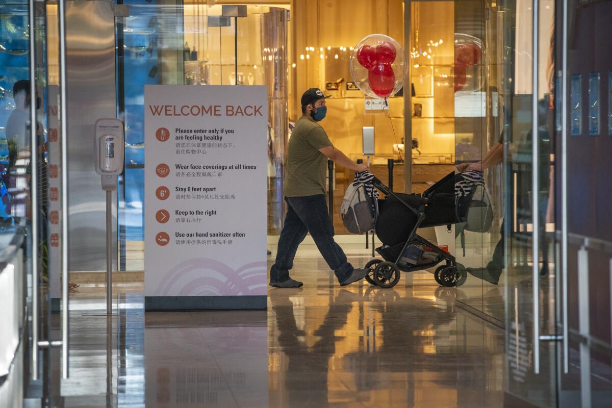 A shopper pushes a stroller past a store in South Coast Plaza in Costa Mesa.