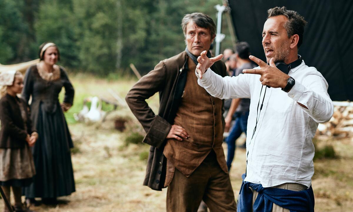 A film director gestures as an actor in period clothing listens on the set of "The Promised Land."
