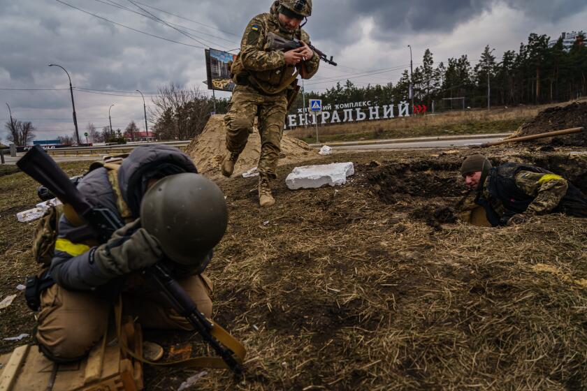 IRPIN, UKRAINE -- MARCH 6, 2022:Ukrainian soldiers rush to brace themselves against incoming artillery fire from Russian forces while defending the town of Irpin and the civilians fleeing it, in Irpin, Ukraine, Sunday, March 6, 2022. (MARCUS YAM / LOS ANGELES TIMES)