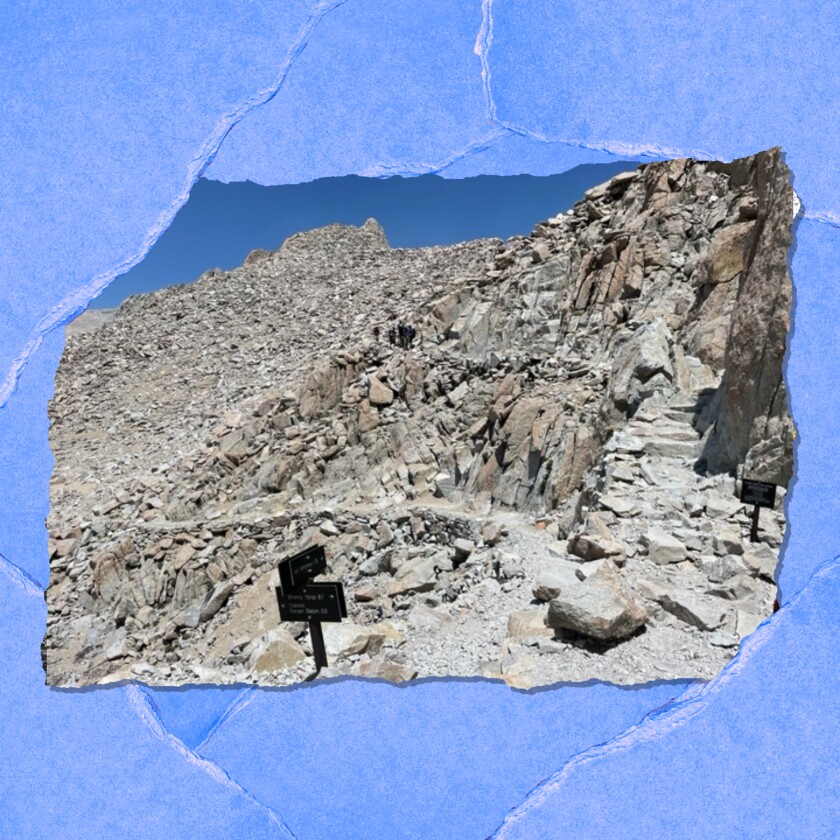 A trail winds through a rocky hillside landscape.