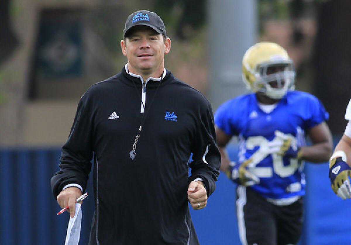 Coach Jim Mora watches practice on the field at UCLA.