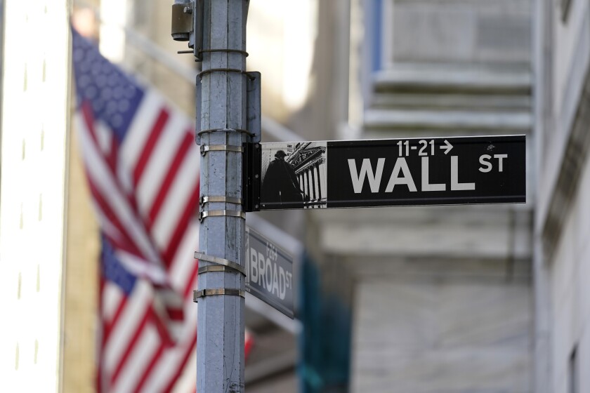 U.S. flags are to the left of a Wall Street sign in front of the New York Stock Exchange.