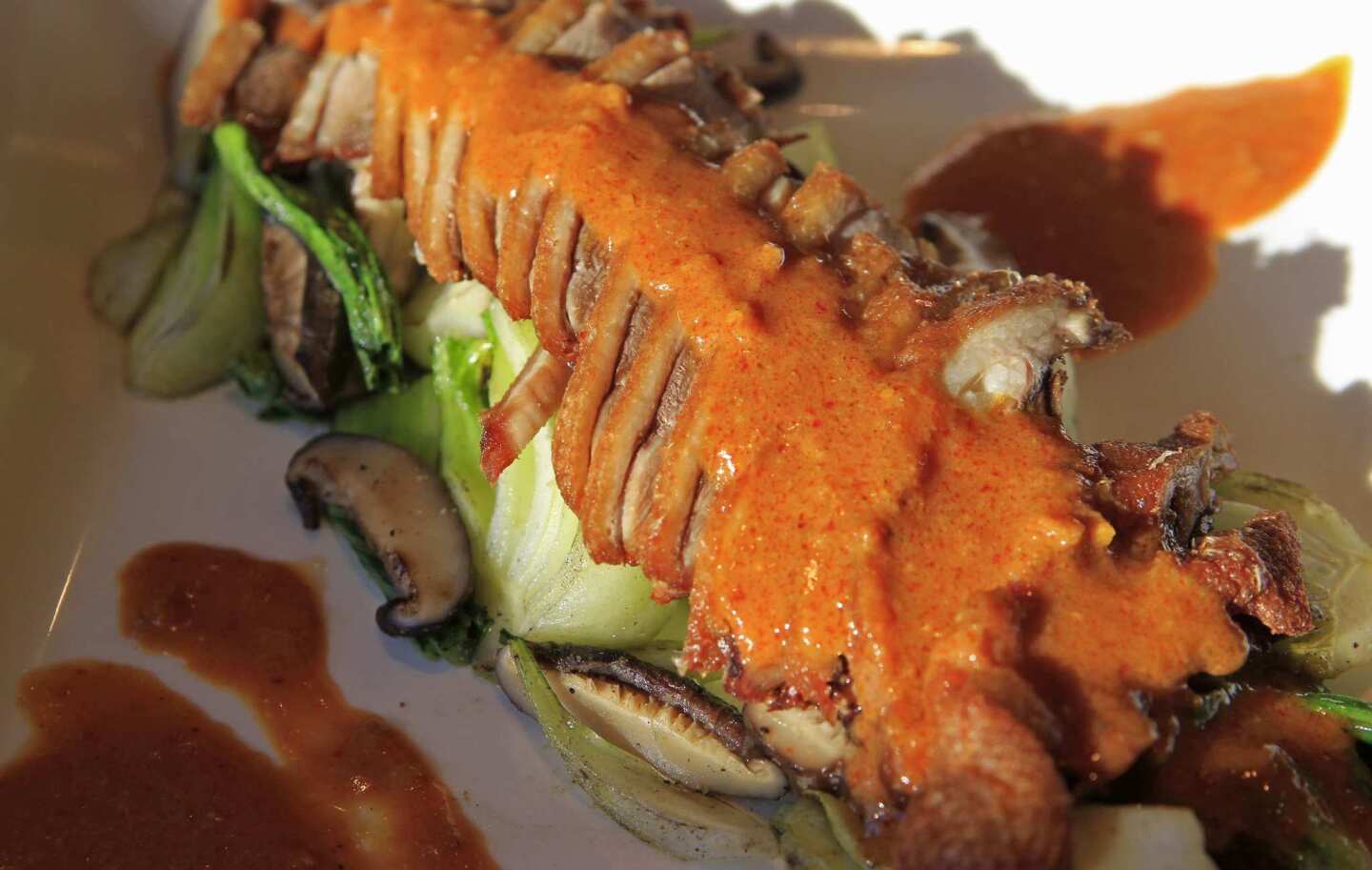 Duck breast, roasted on the bone, is sliced and fanned over baby bok choi and topped with red curry and shiitake mushrooms.