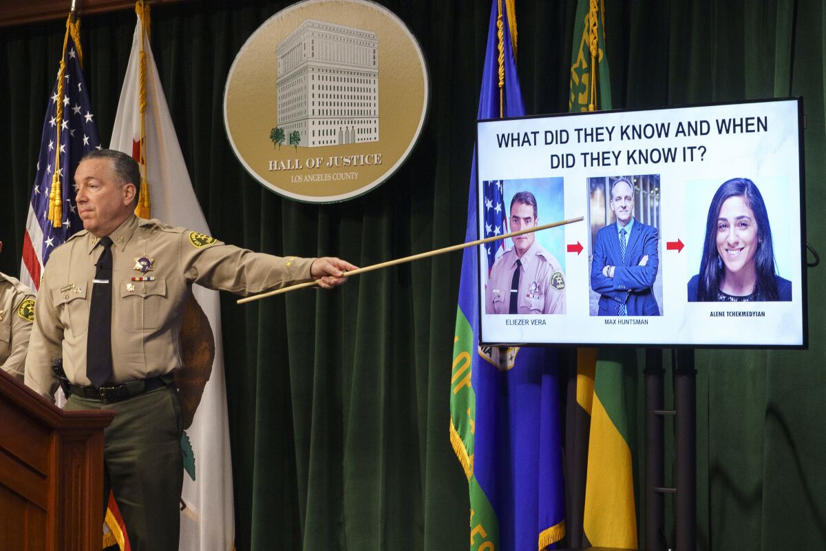 Los Angeles County Sheriff Alex Villanueva holds a pointer against a screen.