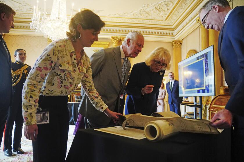 Britain's King Charles III and Queen Camilla are shown Coronation Rolls of previous monarchs after being presented with their own Coronation Roll, an official record of their Coronation, at Buckingham Palace, central London, Wednesday May 1, 2024. King Charles III gaped at the 70-foot-long (21.4-meter) hand-lettered scroll as it was presented to him earlier this week at Buckingham Palace, thanking the artisans who produced the document that serves as the official record of his coronation almost a year ago. (Victoria Jones/PA via AP)