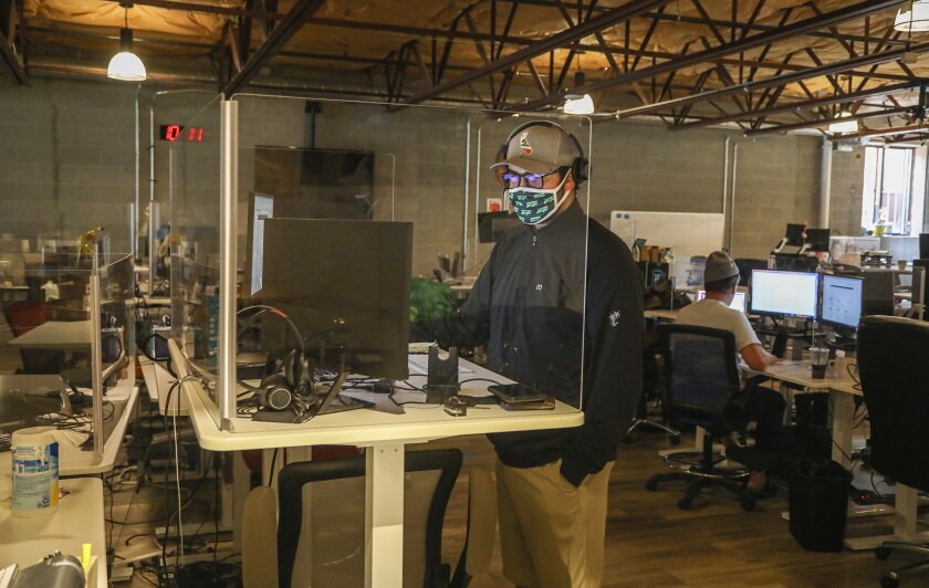 Patrick O'Rourke works behind plexiglass at Flock Freight in their offices Friday, Sept. 4, 2020 in San Diego.