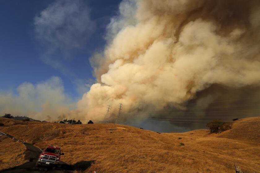GESYERVILLE, CALIF. - OCT. 25, 2019. A firefighter drives his vehicle away from the plume of smoke rising from the Kincade fire on Friday, Oct. 25, 2019. The Kincade fire has charred about 22,000 acres near Geyserville since it started two days ago. (Luis Sinco/Los Angeles Times)