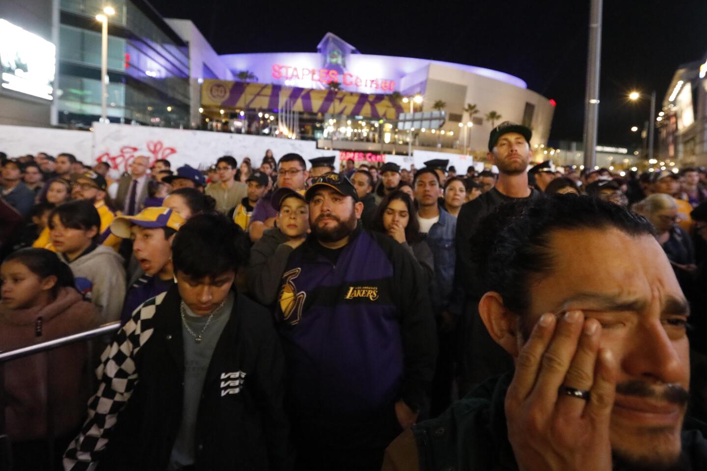 Joseph Hernandez, right, wipes a tear while watching a pregame tribute to Kobe Bryant with hundreds of fans standing outside Staples Center on Jan. 31, 2020.