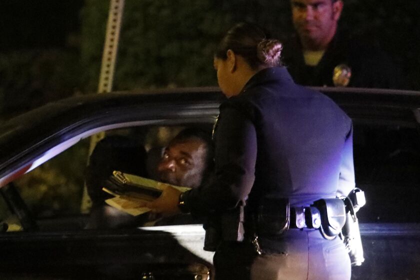 LOS ANGELES, CA - JULY 25, 2019 - - L.A.P.D. officers give a man a ticket for an expired registration in South Los Angeles on July 25, 2019. (Genaro Molina / Los Angeles Times)