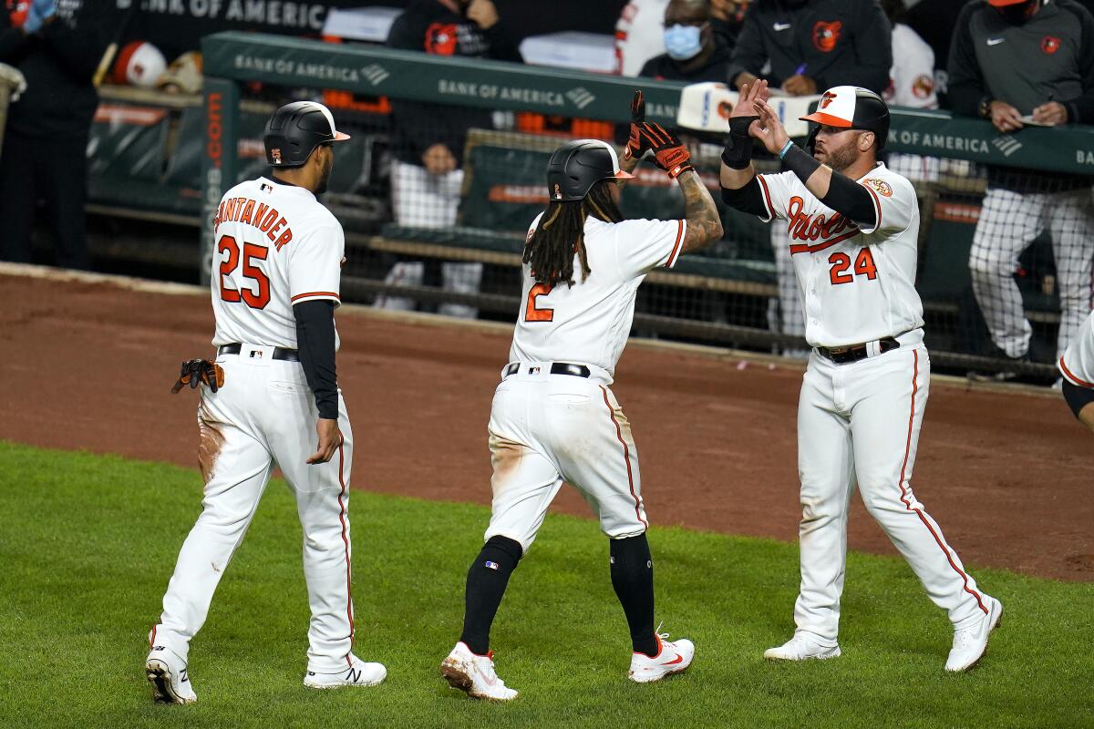 Baltimore Orioles' Anthony Santander (25), Freddy Galvis (2) and DJ Stewart (24) react after they scored on a bases loaded double by Maikel Franco, not visible, during the third inning of the second game of a baseball doubleheader against the Seattle Mariners, Tuesday, April 13, 2021, in Baltimore. (AP Photo/Julio Cortez)