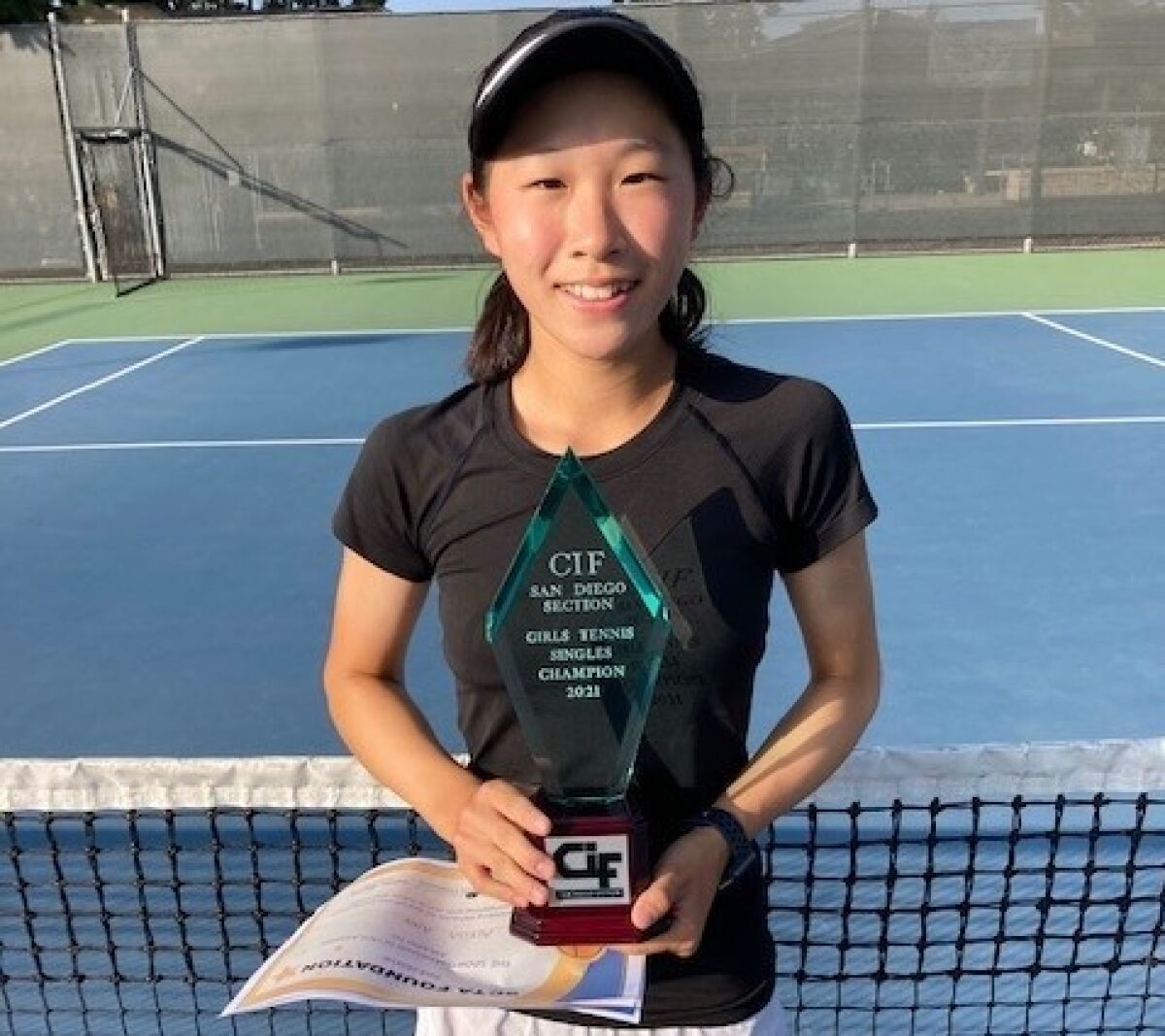 Freshman Alussa Ahn shows toff the trophy for winning the San Diego Section girls tennis title on Friday.