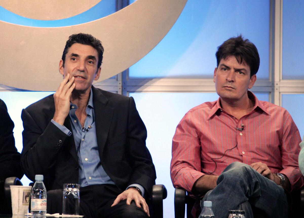 Chuck Lorre, left, sits on a stage next to his then-star Charlie Sheen