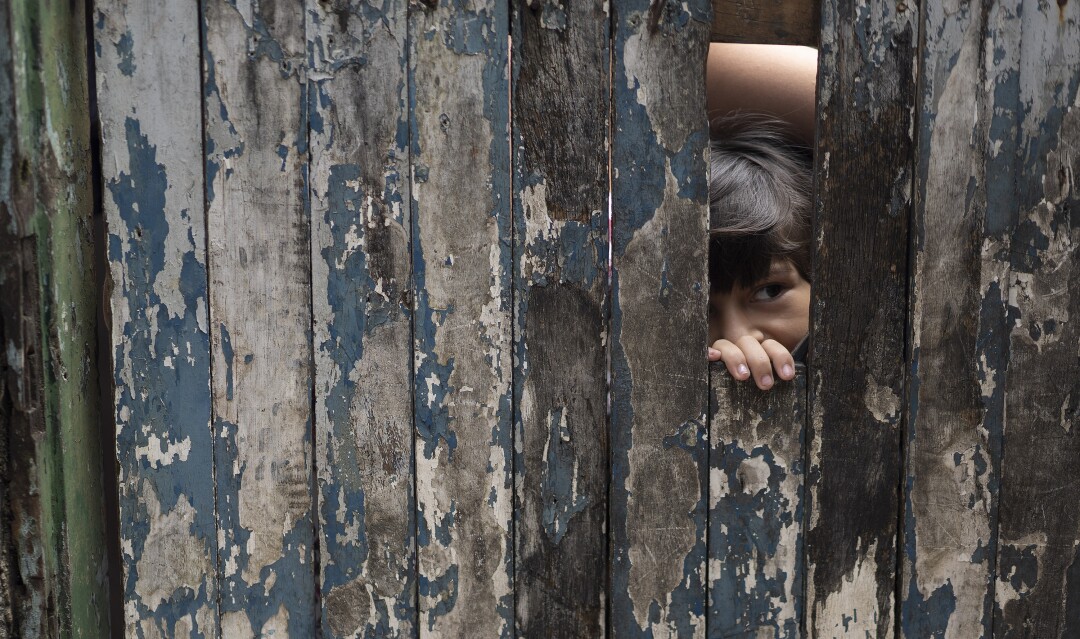 A boy peeks from the doorway of his home in the Rocinha slum of Rio de Janeiro.