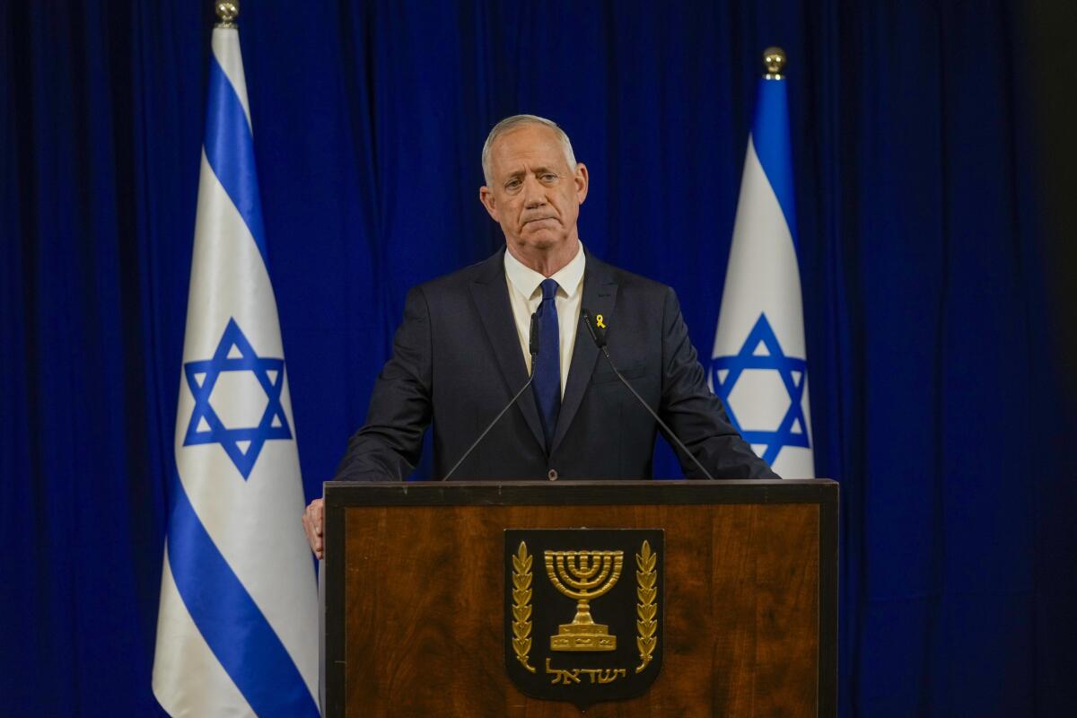 Benny Gantz delivers a statement at a lectern flanked by Israeli flags.