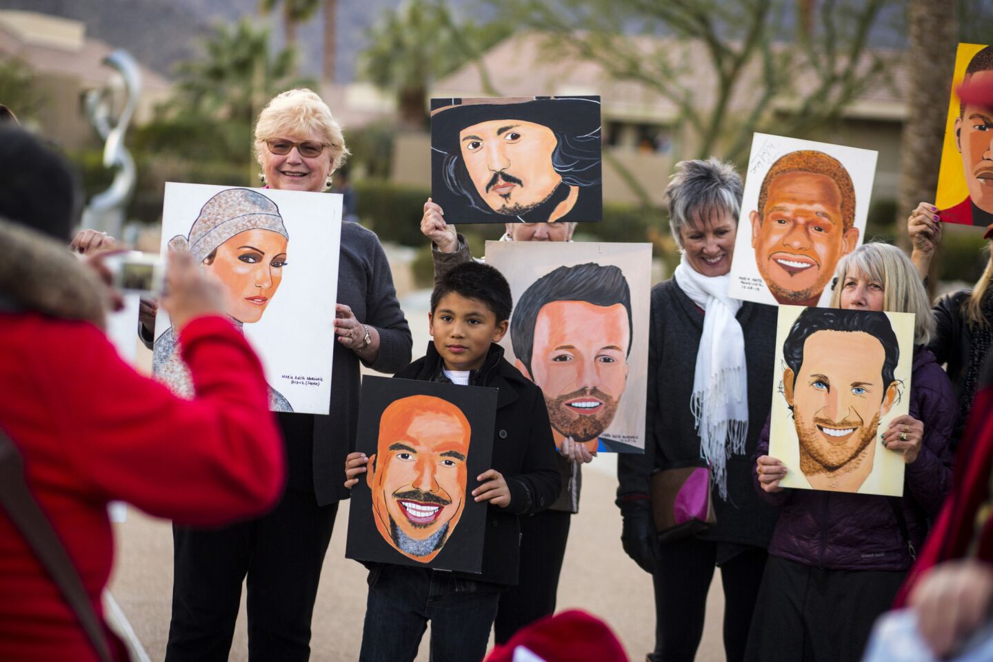 San Antonio artist Maria Anita, left, takes pictures of movie fans holding her celebrity paintings outside the Palm Springs Convention Center.