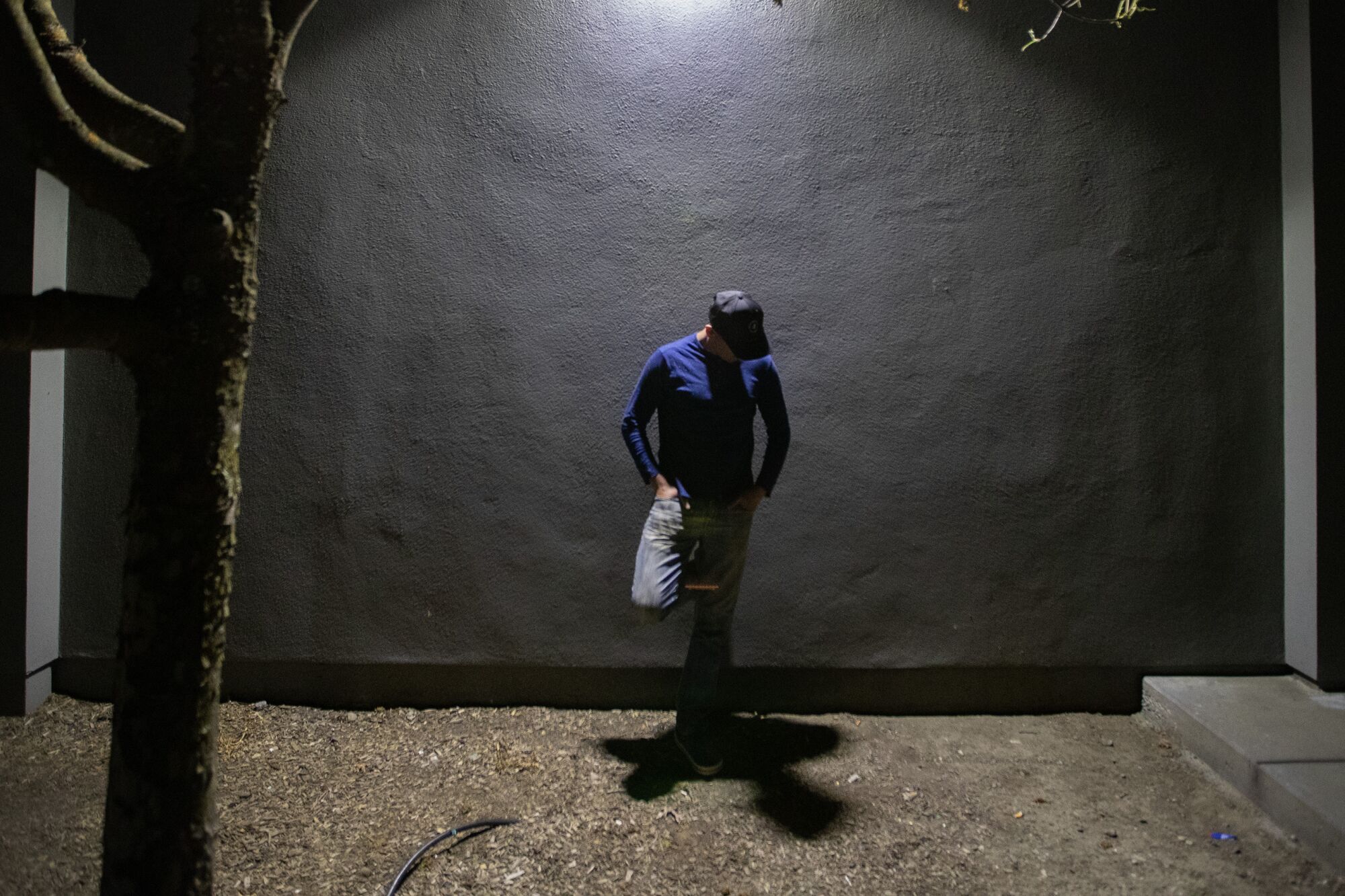 A foreign worker stands in the shadows,
                      obscuring his face.