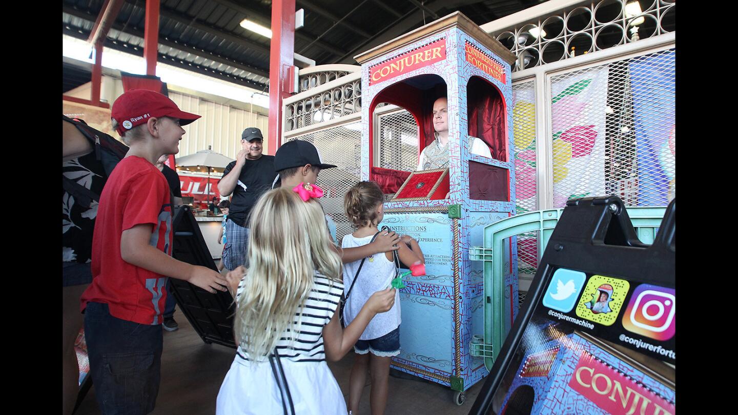 Kids line up to hear Robert Smith, aka Conjurer, tell their fortunes at the OC Fair. When not telling a free fortune, Smith remains motionless, making it hard to tell if he's real or not.