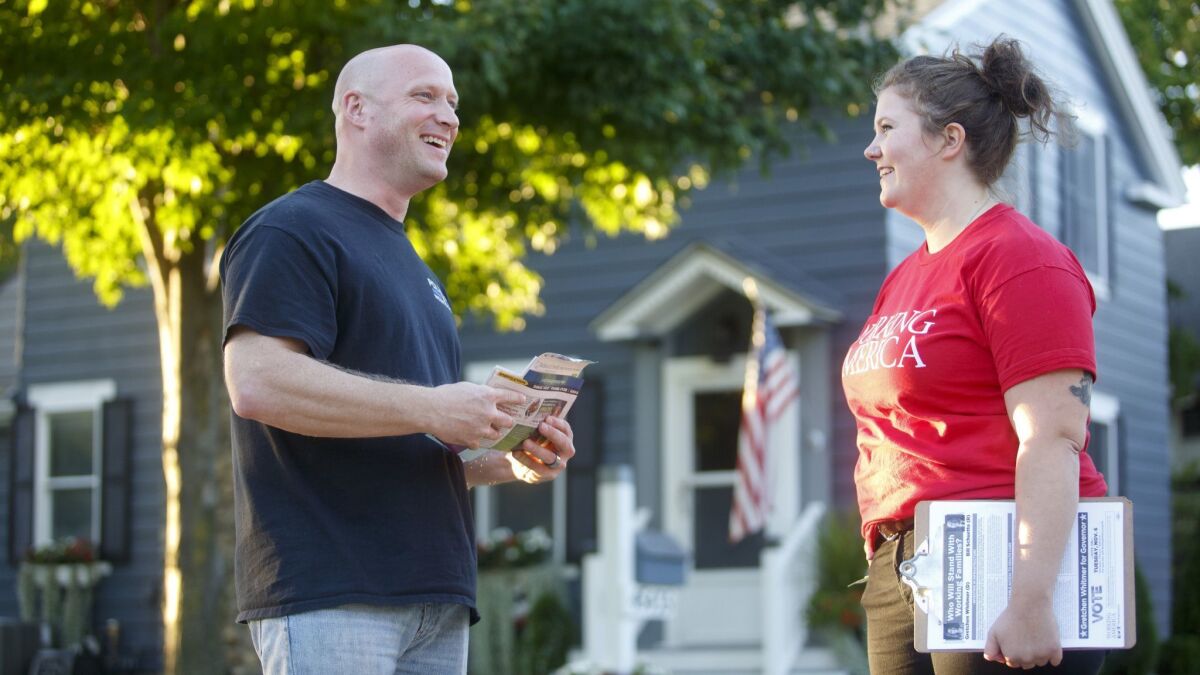 Thom Dionne, 45, left, speaks to Working America canvasser Jaclyn McCann, 28, in Utica, Mich., on Oct. 4. Dionne is a police officer and mayor.