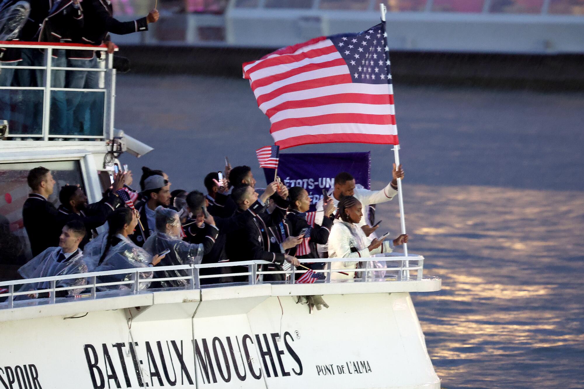 United States' Coco Gauff and Lebron James, front center, travel with teammates along the Seine River.