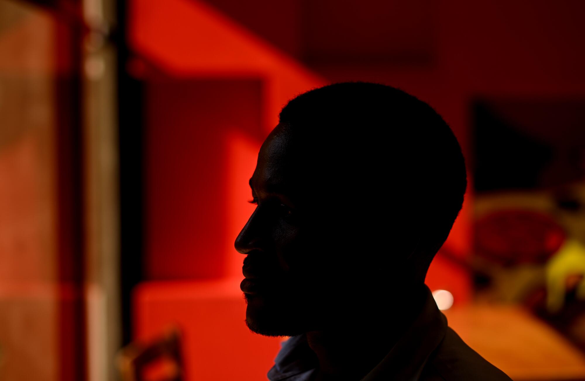 A man is shown in silhouette against a red background