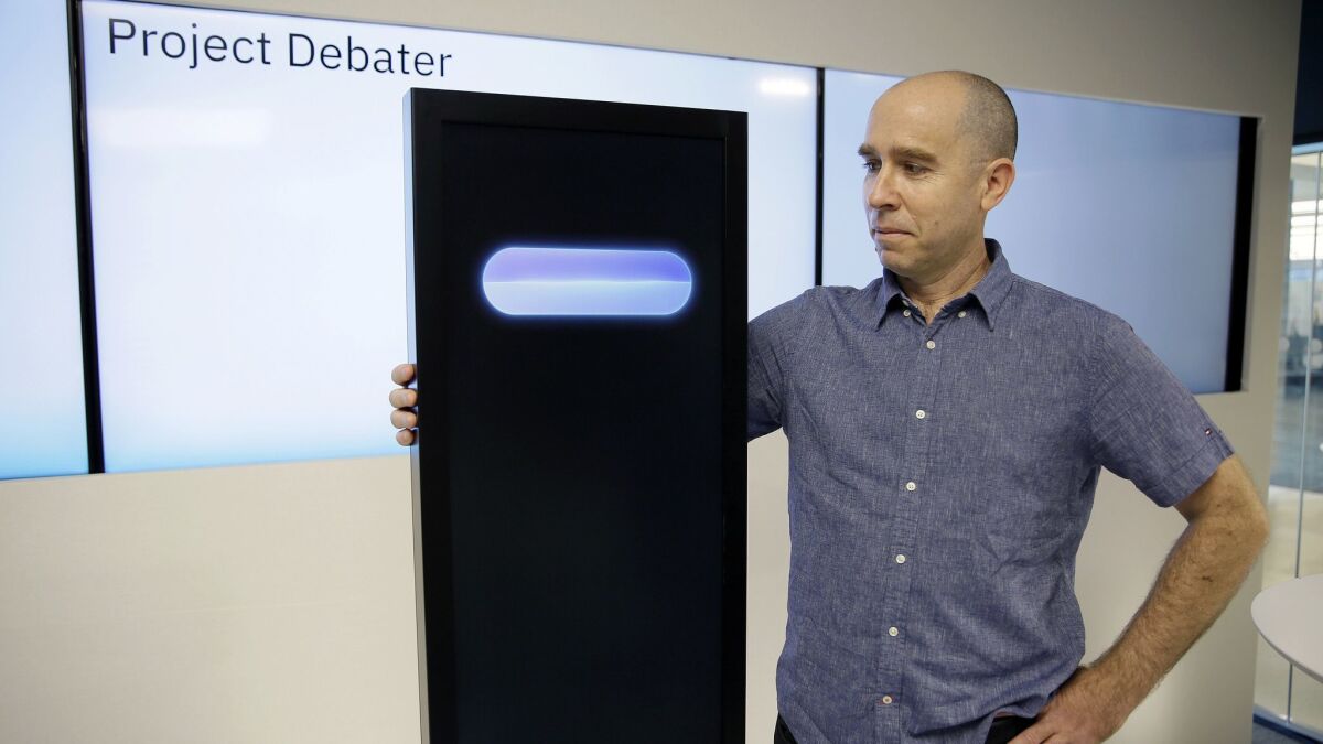 IBM's Project Debater artificial intelligence machine stands alongside Noam Slonim, the project’s progenitor, in 2018.