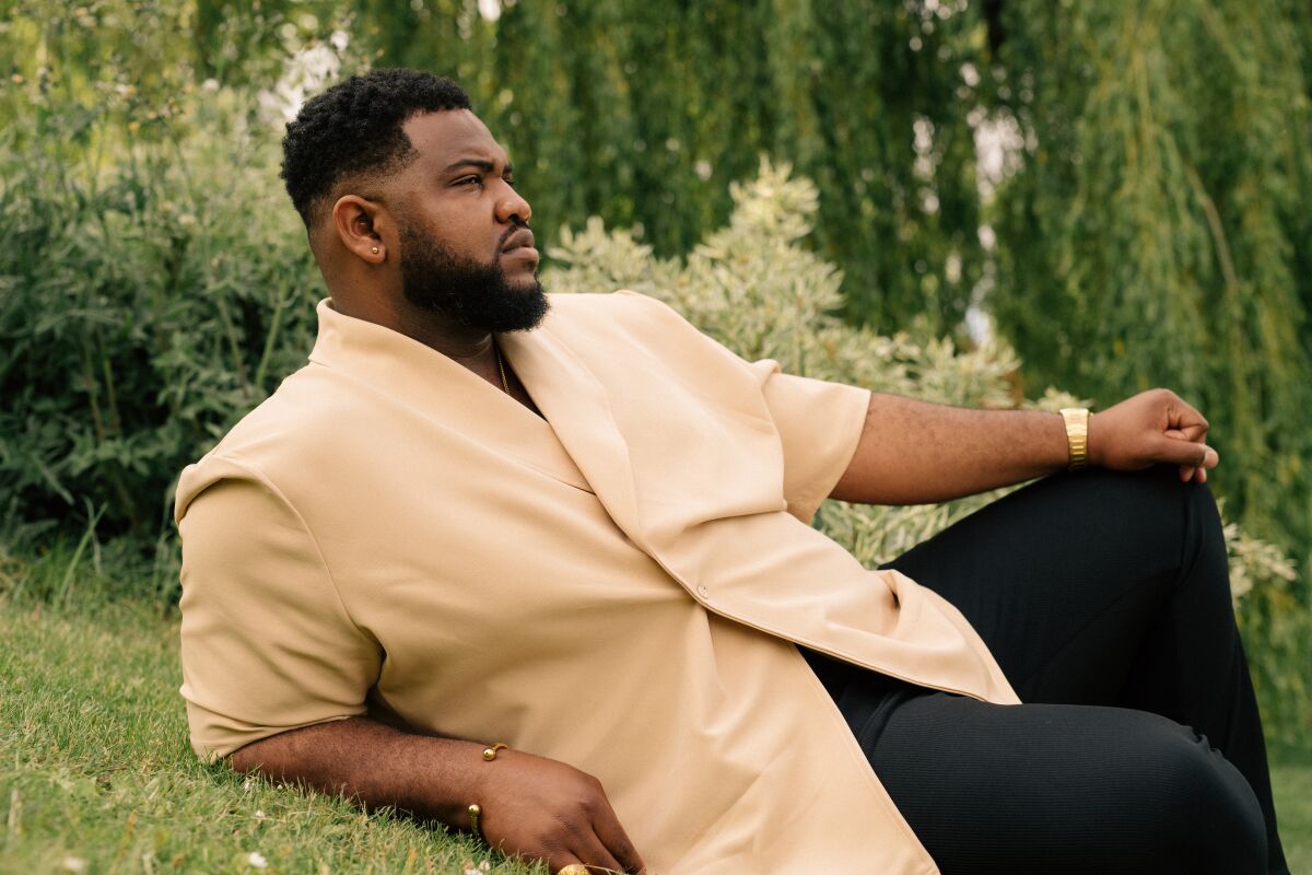 Tobi Bamtefa relaxes in a park for a portrait.