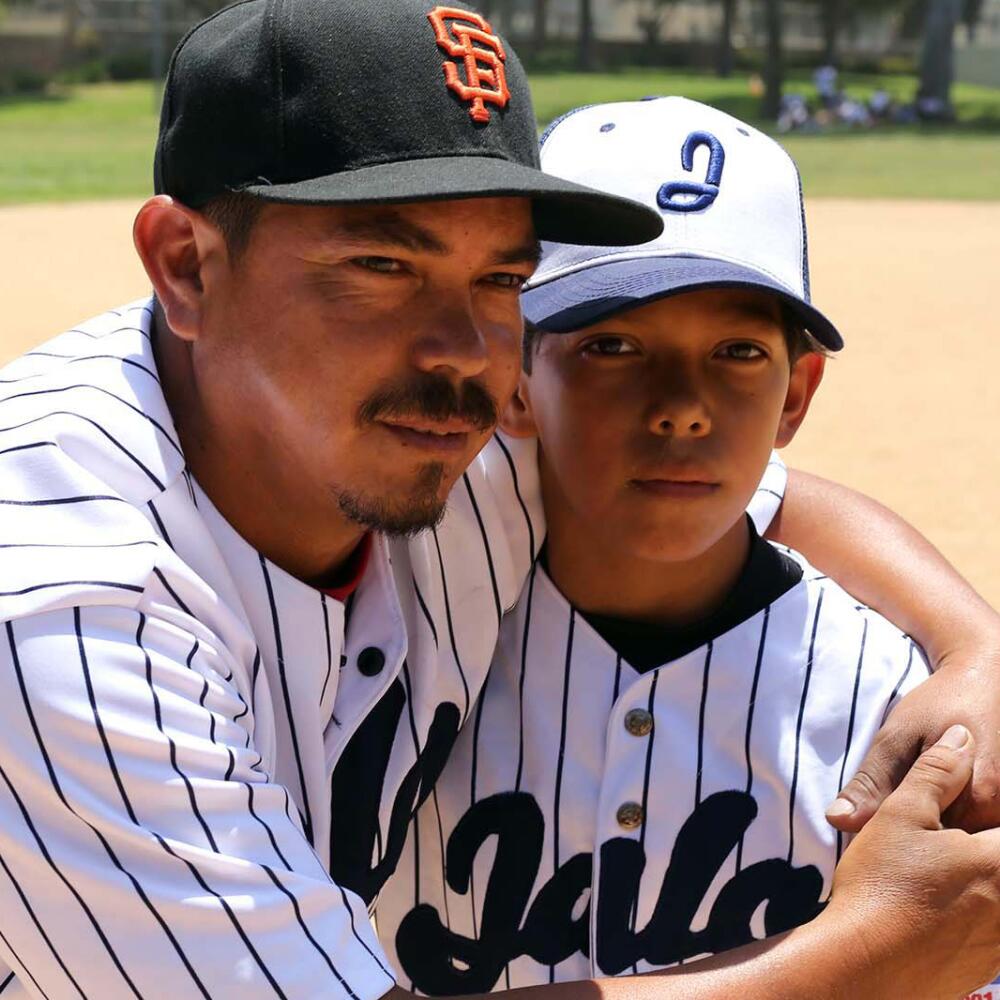 Father and son hug on baseball field