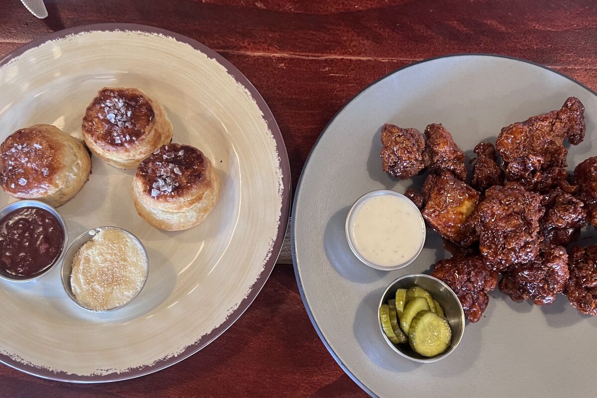 A plate of biscuits next to a plate of fried chicken tenders