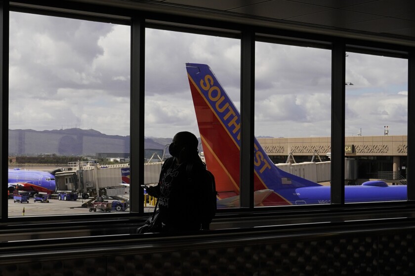 FILE - A passenger walks past a Southwest Airlines plane at Sky Harbor International Airport in Phoenix, March 26, 2021. AT&T and Verizon have agreed to delay the launch of a new slice of 5G service by two weeks after airlines and the nation's aviation regulator complained about potential interference with systems on board planes. (AP Photo/Sue Ogrocki, File)