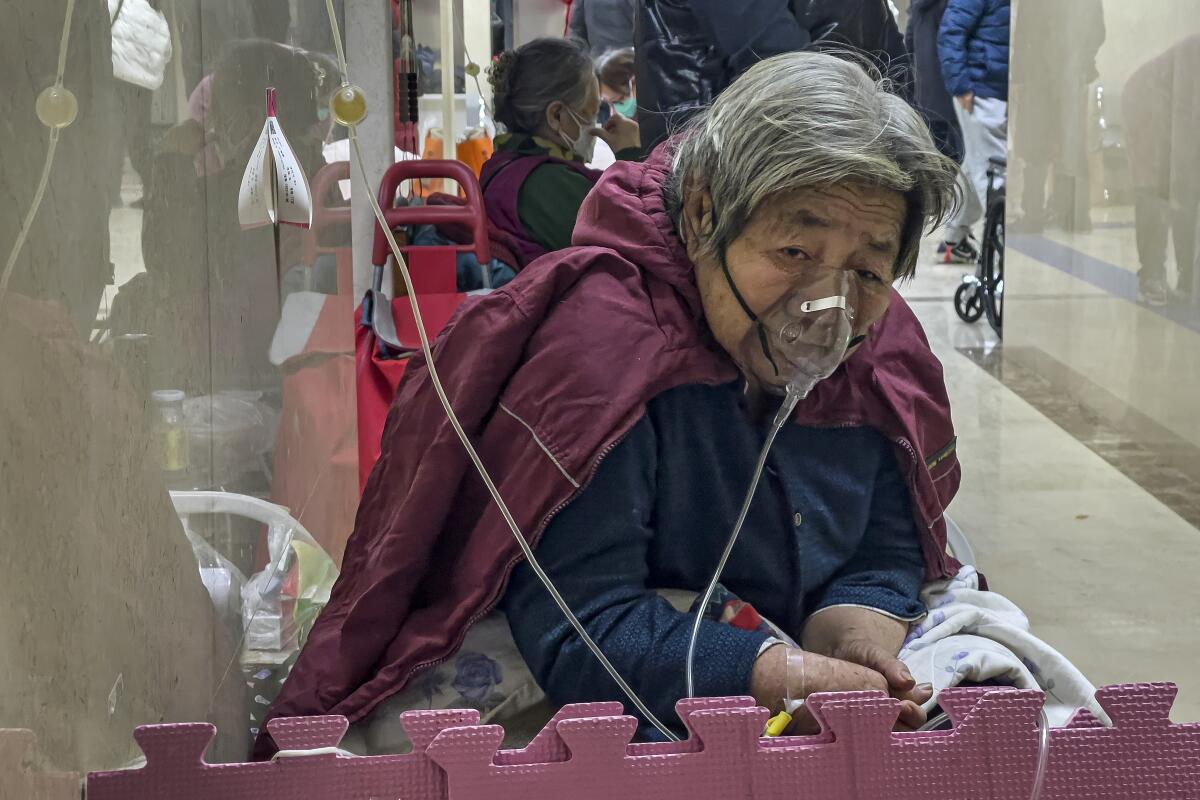 An elderly patient receives an intravenous drip while using a ventilator in the hallway of the emergency ward in Beijing. 