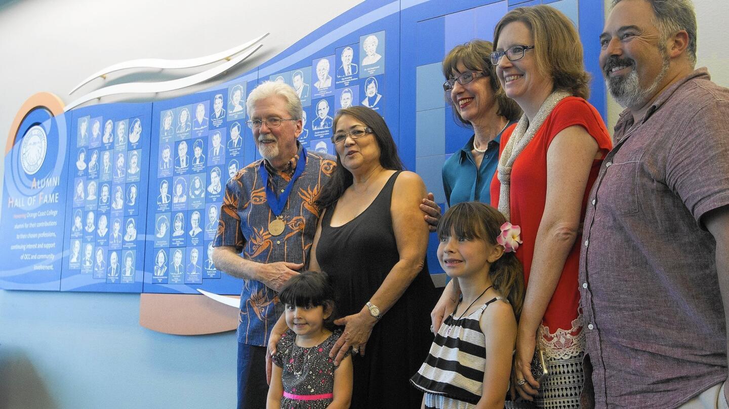 Jim Carnett, left, aka "Mr. OCC," poses for photos with his family in front of the Alumni Hall of Fame wall at Orange Coast College Library on Thursday.