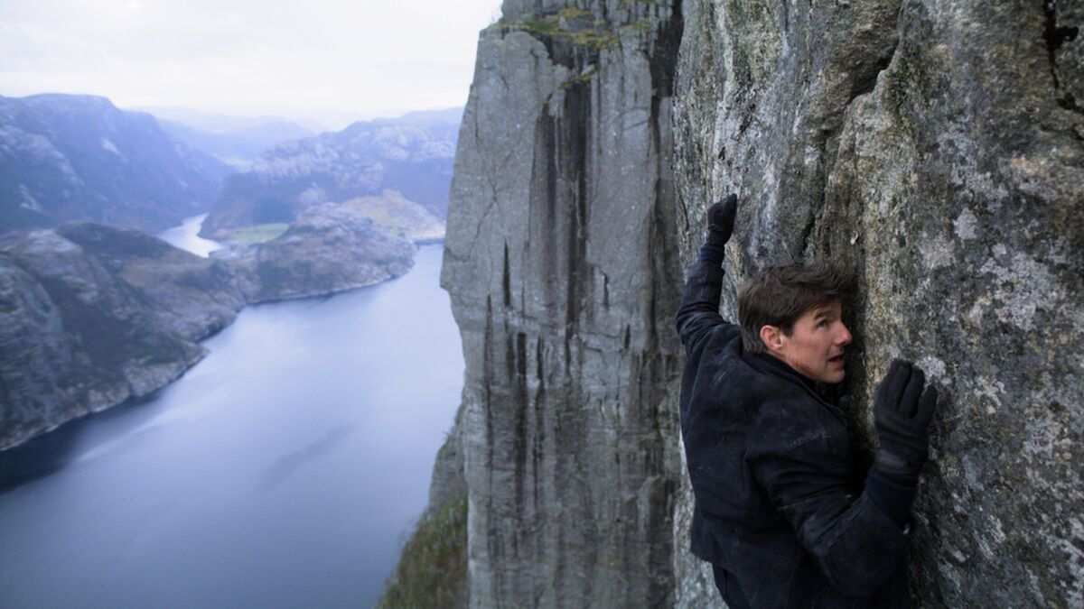 Tom Cruise clings to the side of a mountain