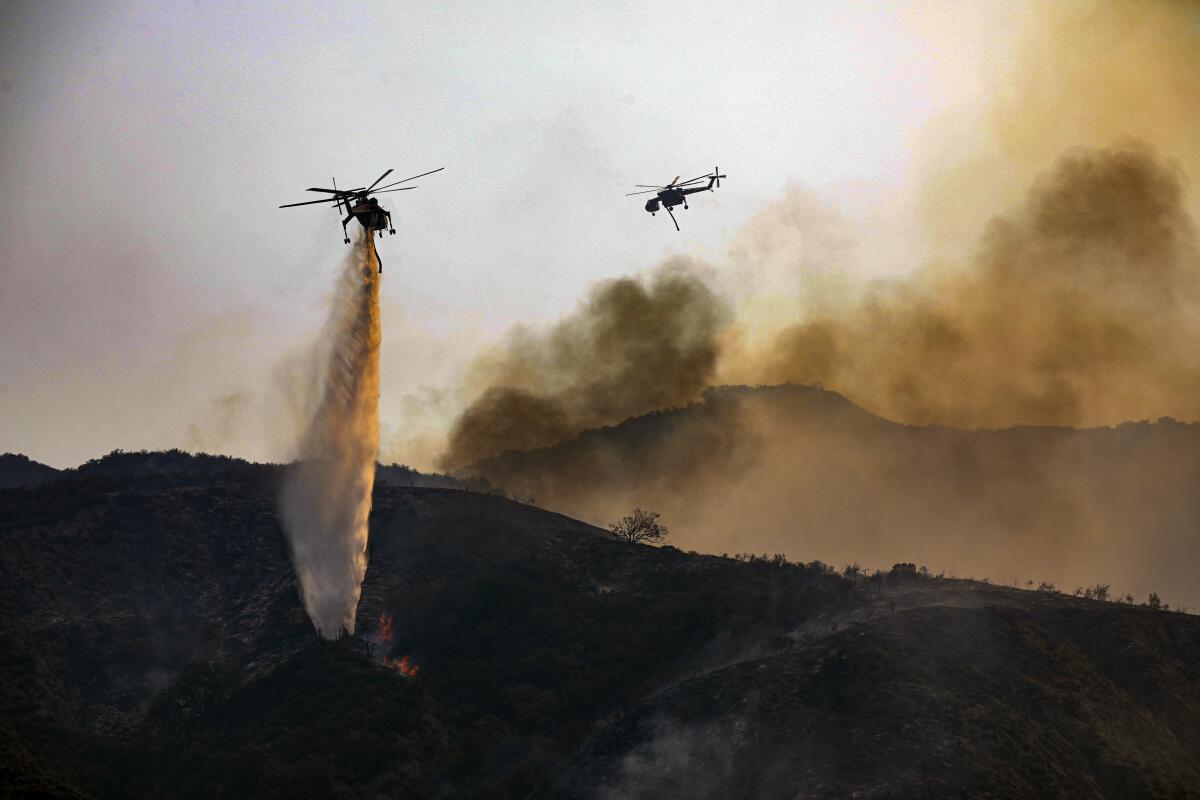 Helicopters above a fire with smoke in the background