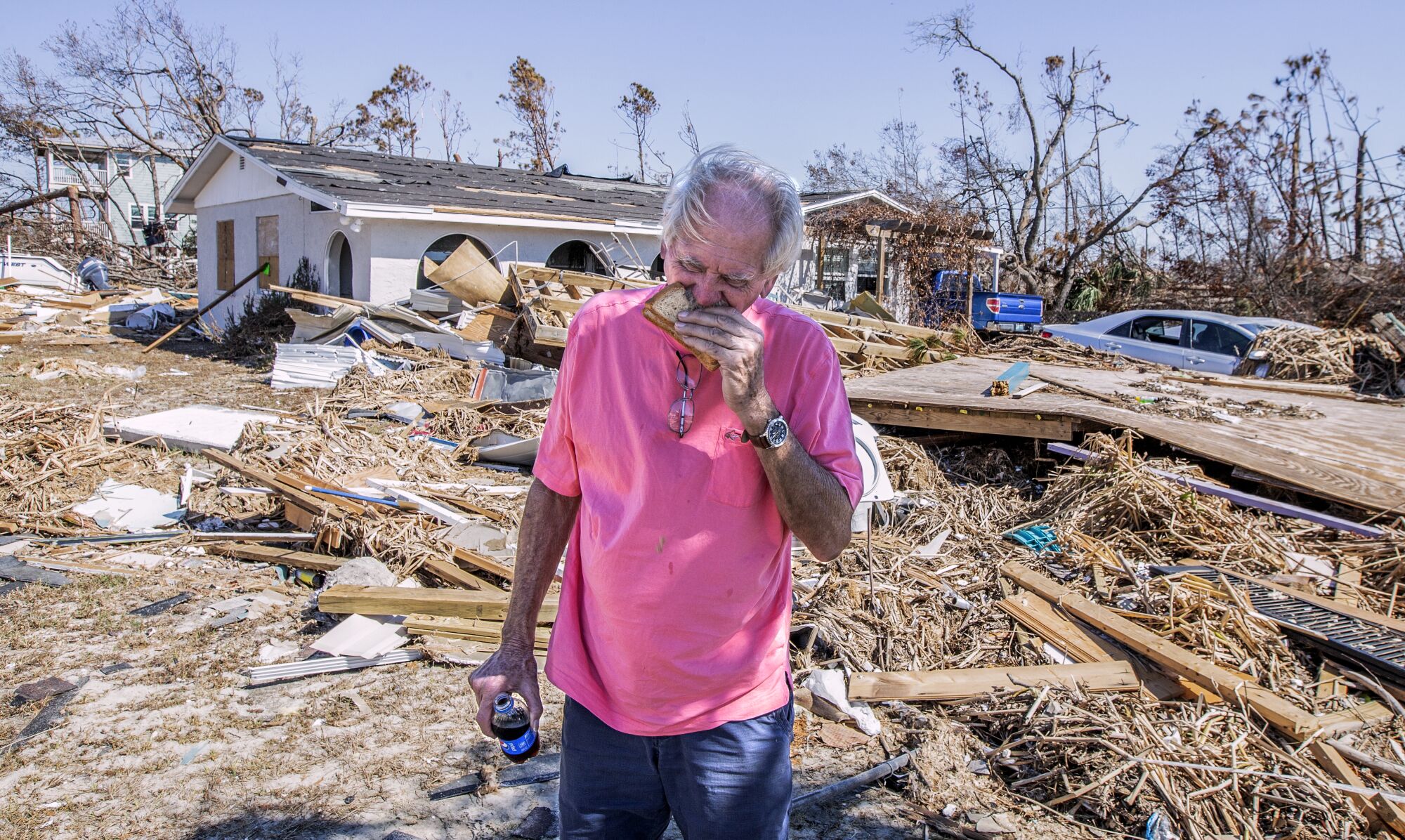Mike Danner grabs a quick lunch eating a sandwich in front of his damaged home.