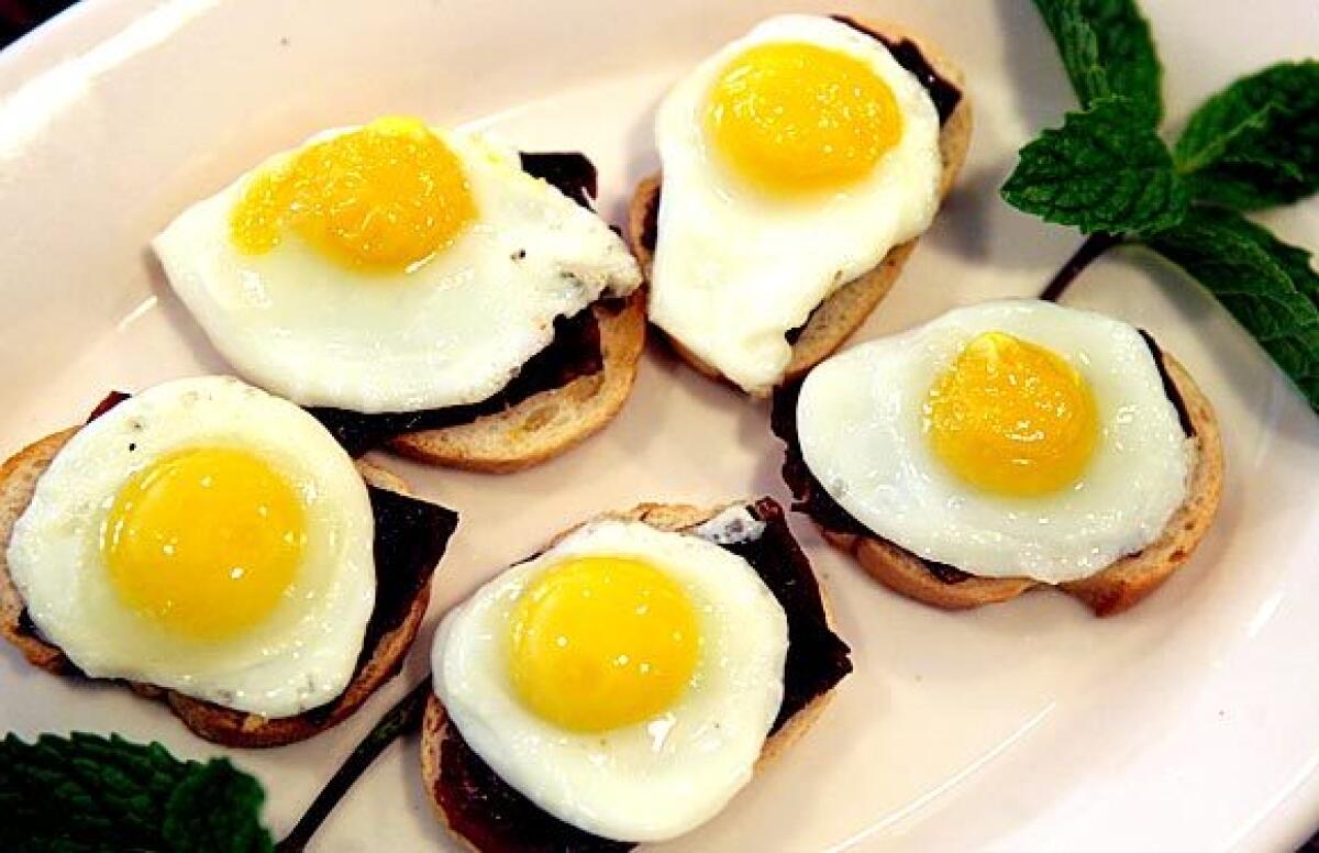 Baguette rounds are topped with thinly sliced basturma and a quail egg.