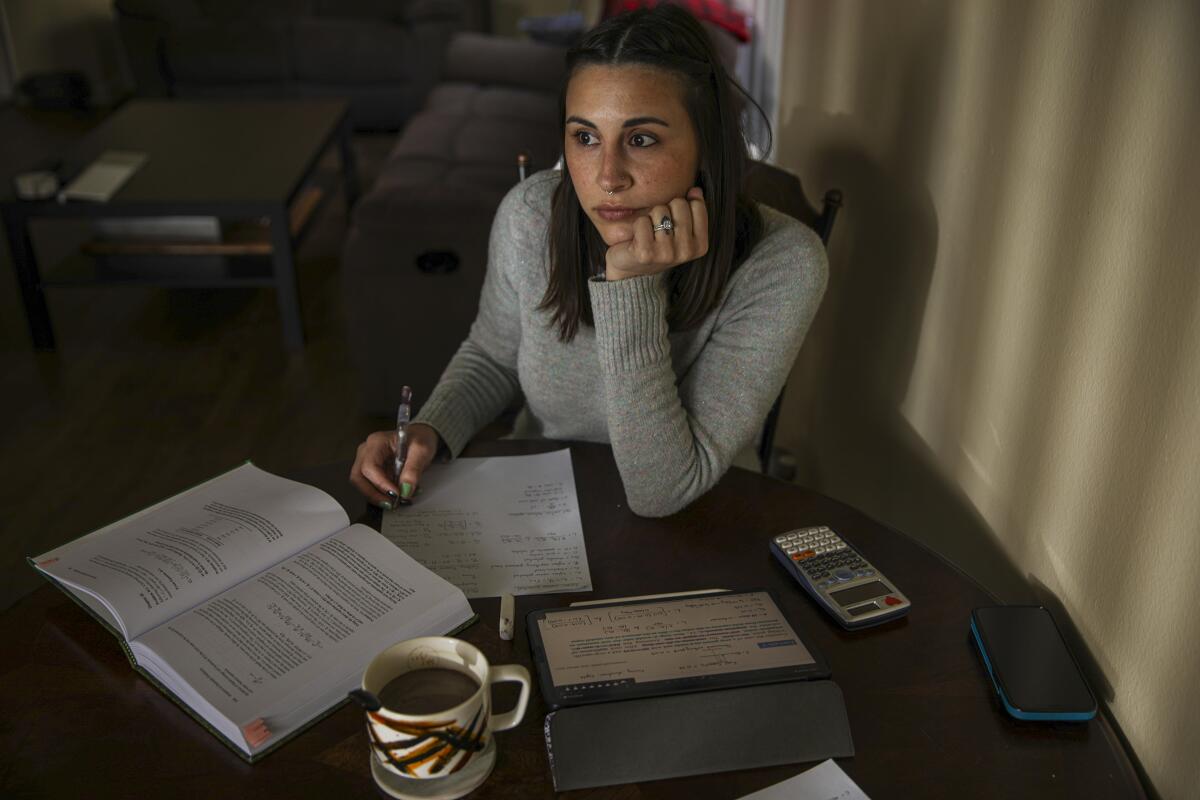 Casaundra Caruso rests her head in her palm while working on math schoolwork at her table