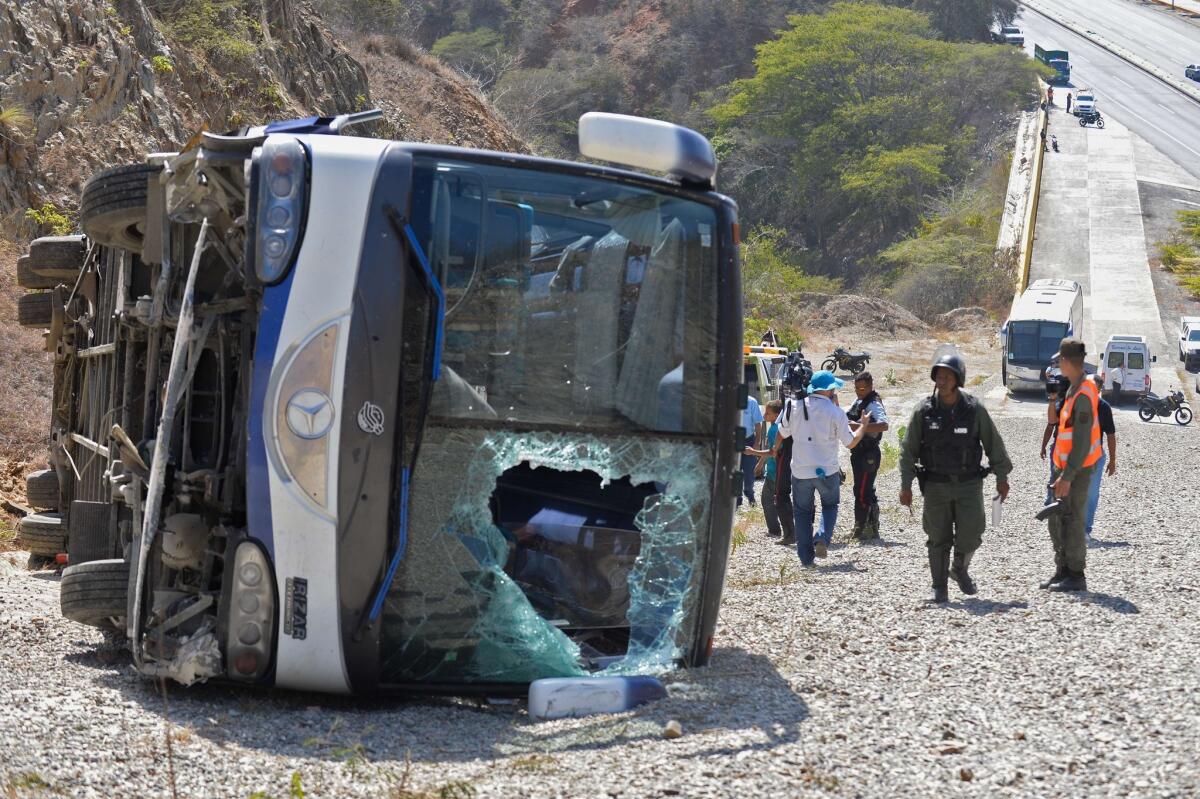 People remain near an overturned bus -which transported Argentinian football team Huracan's players- after an accident at the Caracas-La Guaira highway in Caracas on February 10, 2016. Huracan's coach and five players were injured on Wednesday after the bus taking them to Simon Bolivar International Airport overturned, a day after their Copa Libertadores football match against Caracas FC. AFP PHOTO / FEDERICO PARRAFEDERICO PARRA/AFP/Getty Images ** OUTS - ELSENT, FPG, CM - OUTS * NM, PH, VA if sourced by CT, LA or MoD **